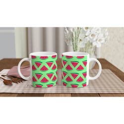 Two ceramic mugs featuring a cute pattern of red watermelon slices on a bright green background, set on a checkered placemat.