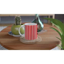 Red striped ceramic coffee mug on a wooden table, candy-cane style, with a small cactus and green vase nearby.