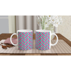 Two glossy ceramic mugs featuring a retro pink and aqua herringbone geometric pattern sitting on a checkered placemat.