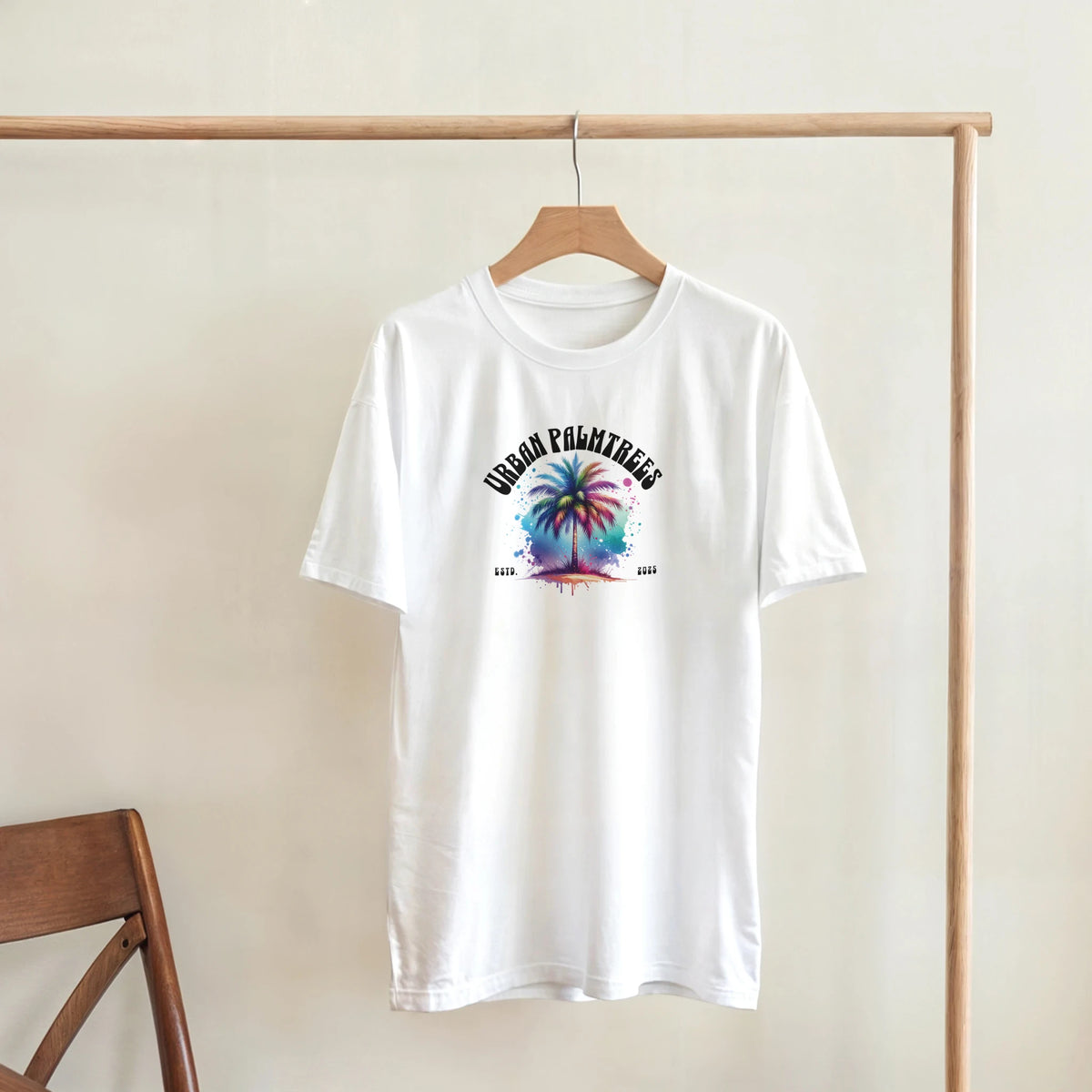 White Urban Palm Trees T-Shirt on a wooden hanger featuring a colorful palm tree graphic.