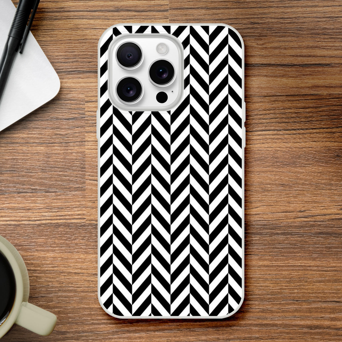 Black and white geometric herringbone iPhone case on wood. Shock-absorbing TPU phone cover with crisp matte finish for iPhone 13-16.