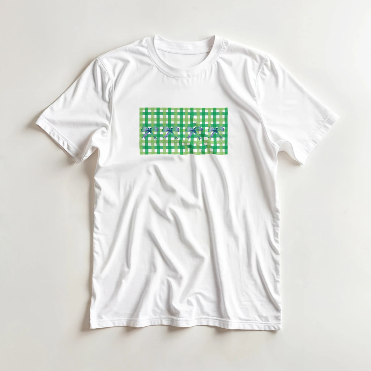 White T-shirt featuring a green gingham square with blue bow accents on the front.