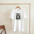 White women's graphic tee in a cotton-blend, featuring Tropical Paradise black silhouette of a woman with palm leaves.