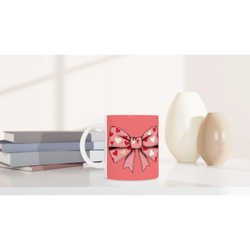 Cute pink and cream Coquette Bow Mug with heart bow design, on desk near pastel books.