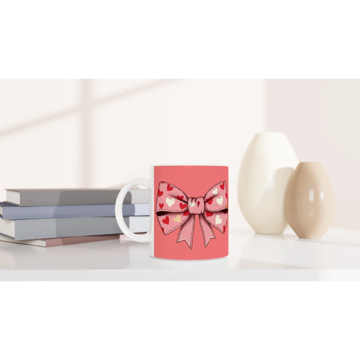 Cute pink and cream Coquette Bow Mug with heart bow design, on desk near pastel books.