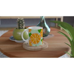 Cute orange mug with citrus slice design on mint-green background, set on a wooden table beside a cactus.