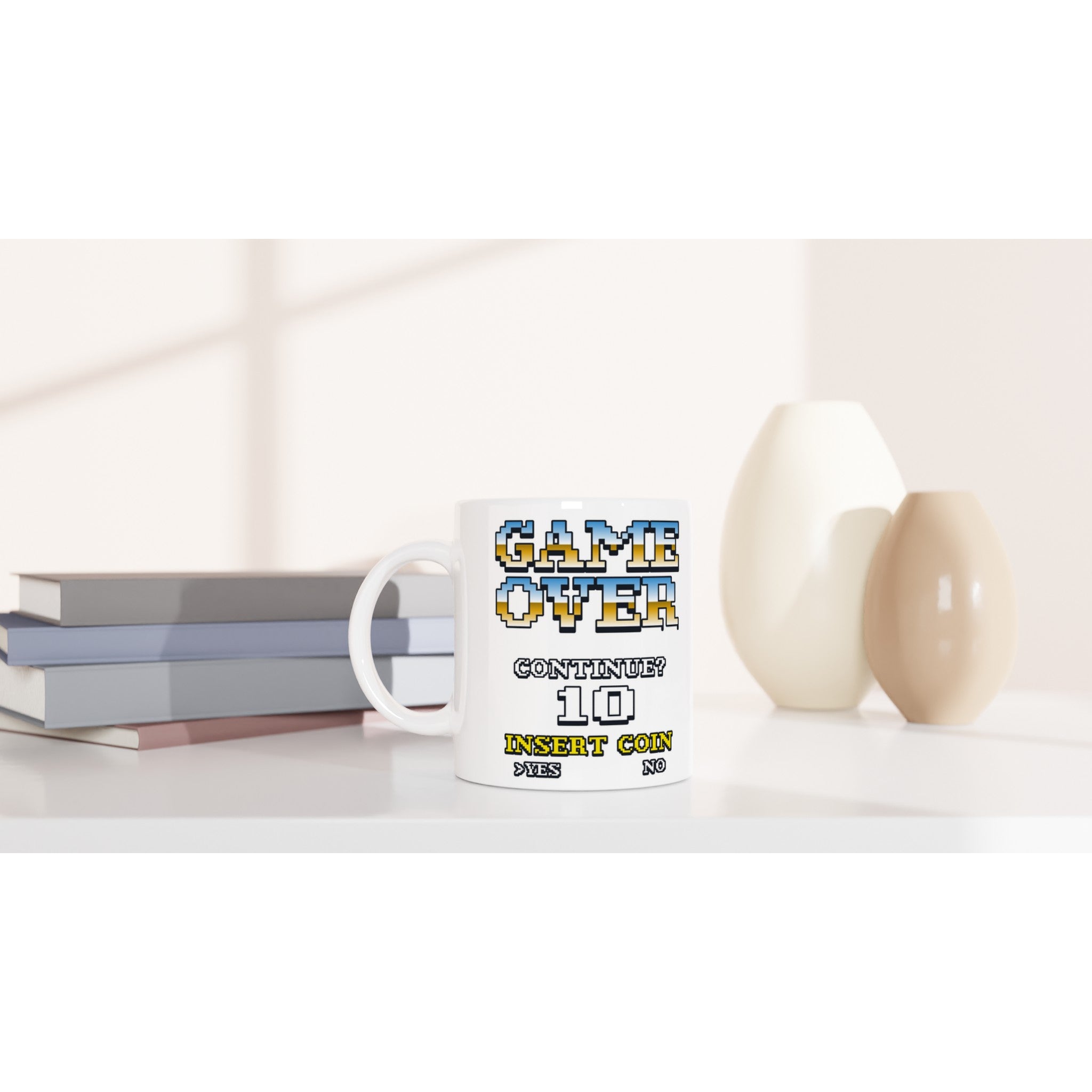 White ceramic 11 oz mug with retro pixel art 'GAME OVER' and 'INSERT COIN' on a desk.