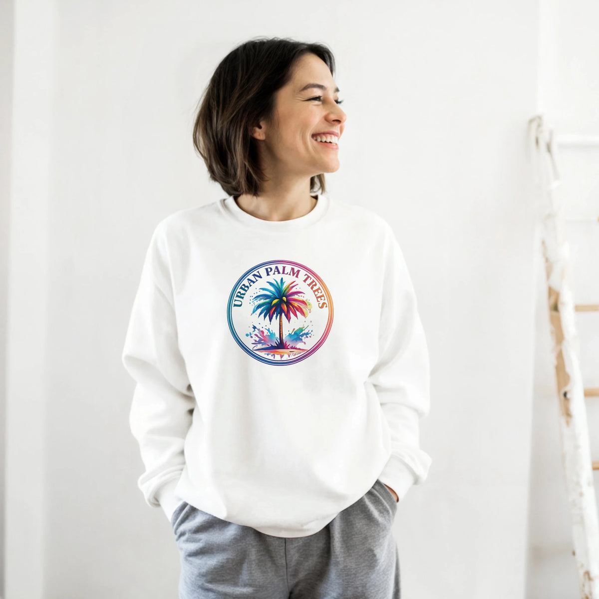Smiling woman wearing a white Urban Palm Trees Sweatshirt with a colorful circular palm design.
