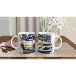 Pair of glossy white ceramic mugs with blue JDM drift car graphics on a checkered placemat.