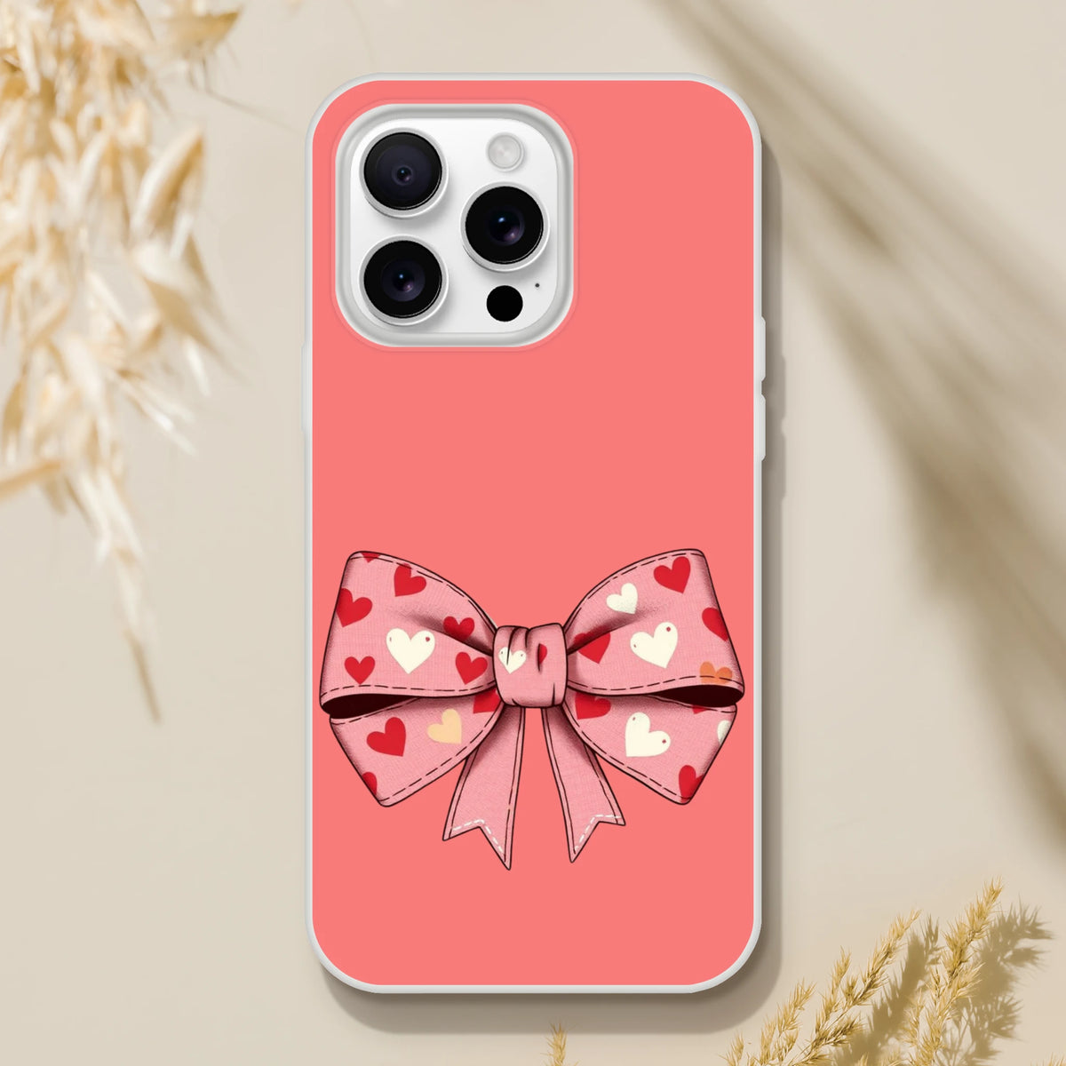 Pink iPhone case with a heart-pattern bow design for iPhone 13–16, Coquette aesthetic.