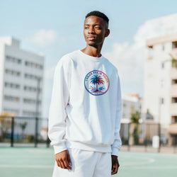 Man wearing white Urban Palm Trees Sweatshirt with palm graphic against an urban backdrop, Y2K streetwear vibe.