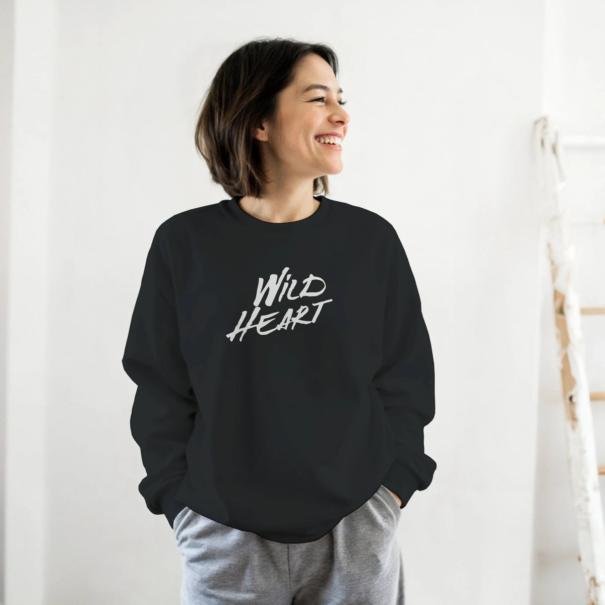 Smiling woman wearing a black Cute Wild Heart sweatshirt with a bold white slogan.