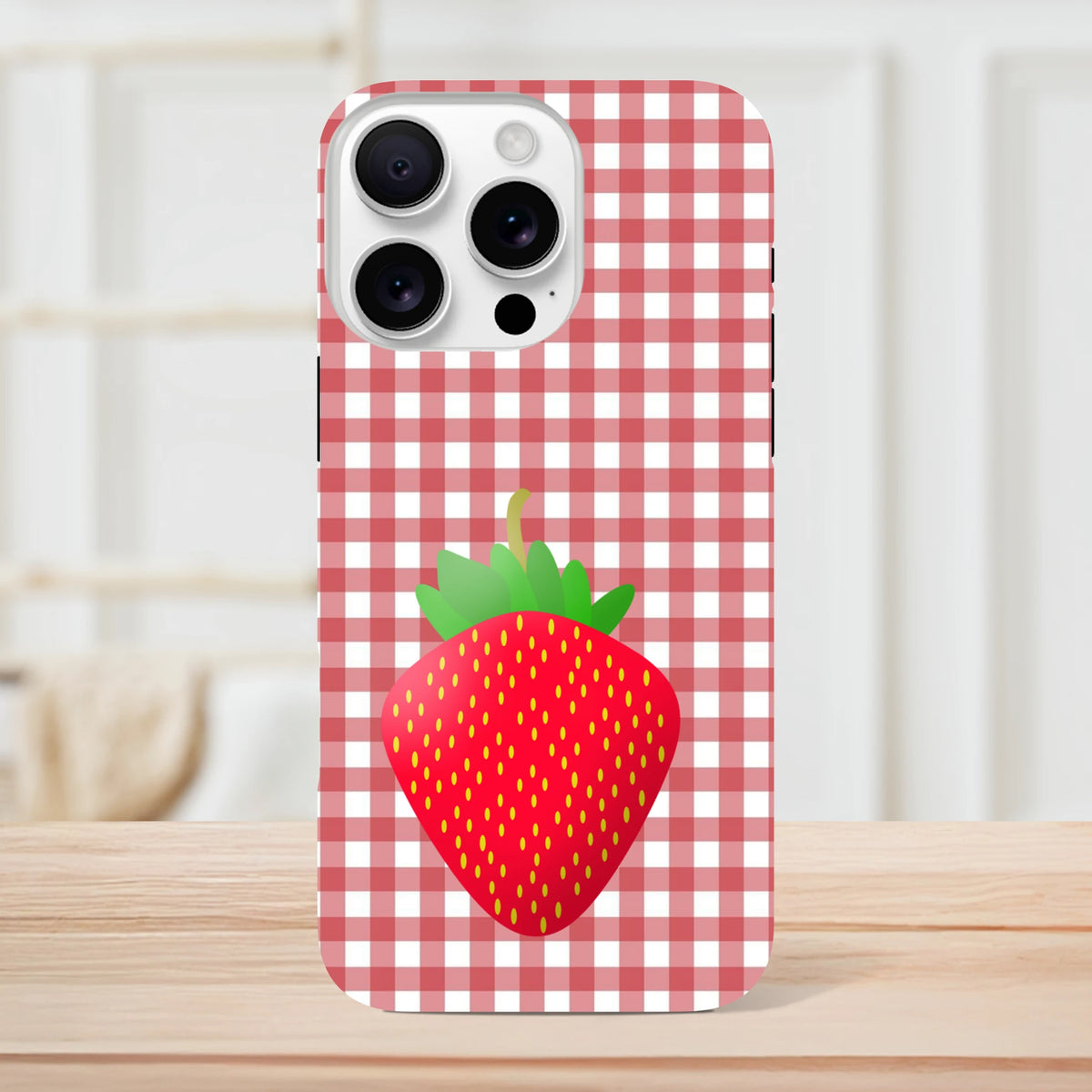 Red gingham iPhone case featuring a large bright red strawberry graphic, offering rugged drop protection for daily use.