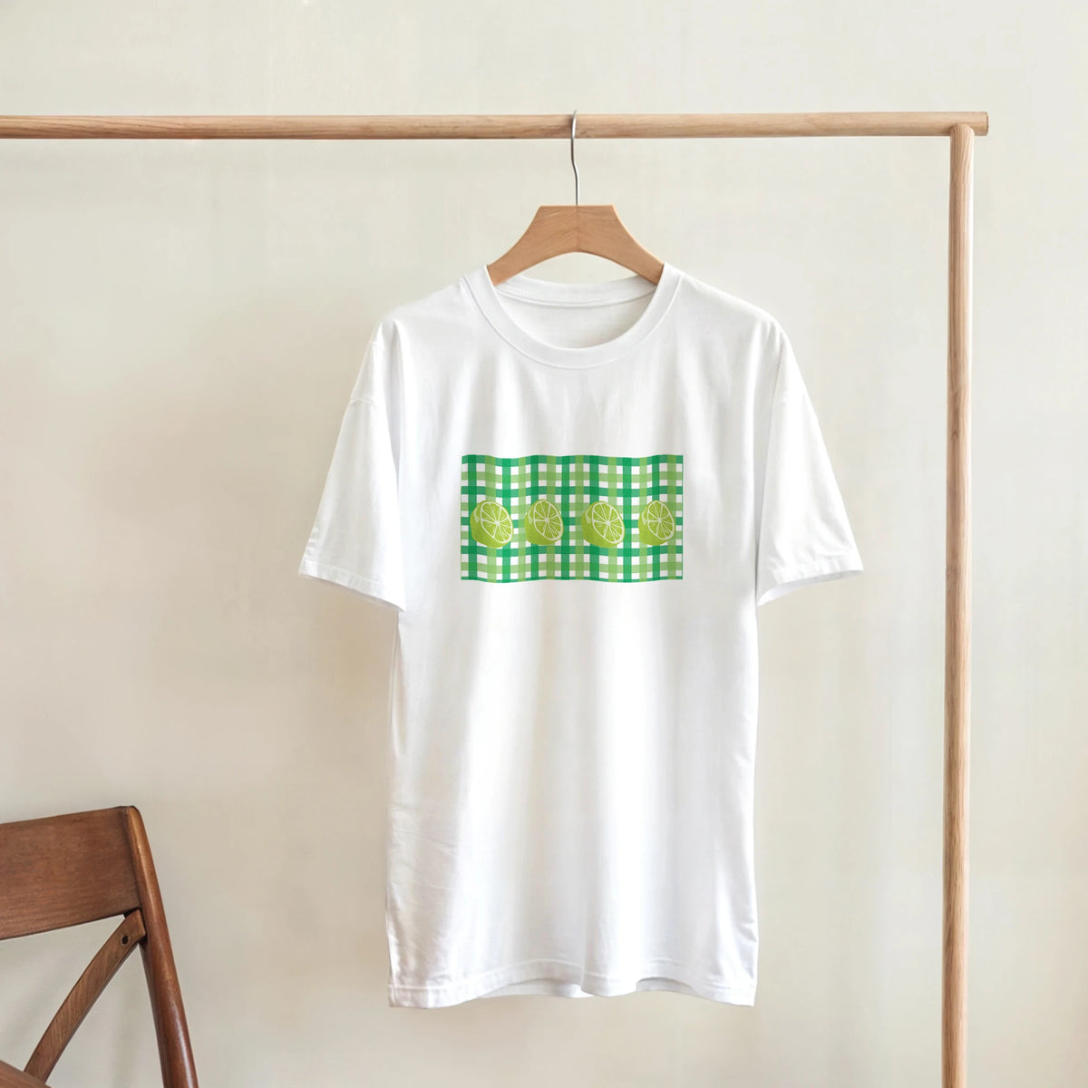 White T-shirt with lime gingham graphic on front, hanging on a wooden hanger.