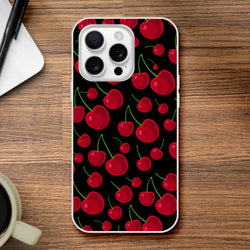 Black iPhone case featuring a retro red cherry pattern with green stems, shown on a wooden desk next to a notebook and coffee cup.
