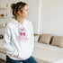Woman wearing white cotton-blend hoodie with pink cherry graphic, cozy pullover.
