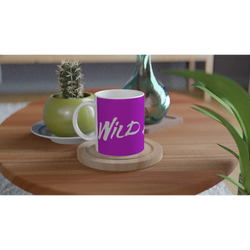 Purple Cute Wild Heart Mug with slogan sits on a wooden table beside a cactus and a vase.