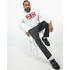 Man modeling a white Union Jack Hoodie with bold flag graphic, gray pants, black loafers, seated on a stool.