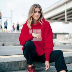 Woman in red retro strawberry gingham hoodie featuring a vintage fruit graphic, styled with black pants for urban athleisure.