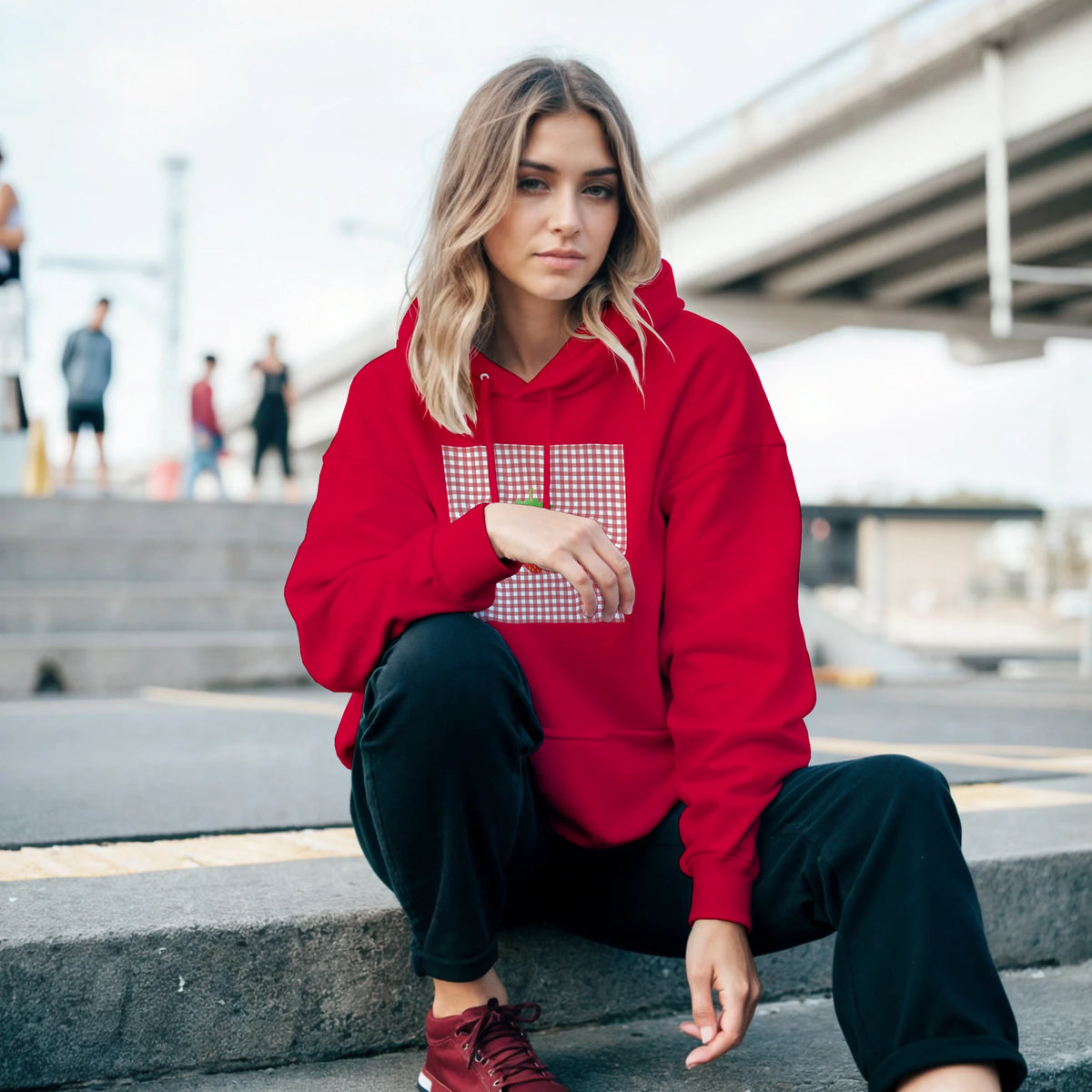 Woman in red retro strawberry gingham hoodie featuring a vintage fruit graphic, styled with black pants for urban athleisure.