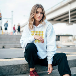 Woman wearing Retro Banana Gingham hoodie with vintage fruit graphic and yellow gingham on urban steps.