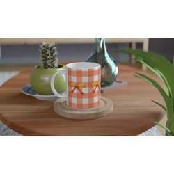 Orange gingham bow mug on a wooden table, with a small cactus and vase nearby.