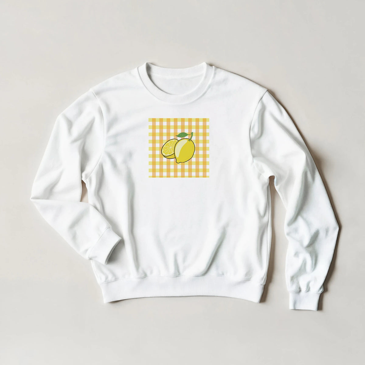 White sweatshirt featuring a retro yellow gingham square graphic with whole and sliced lemons.