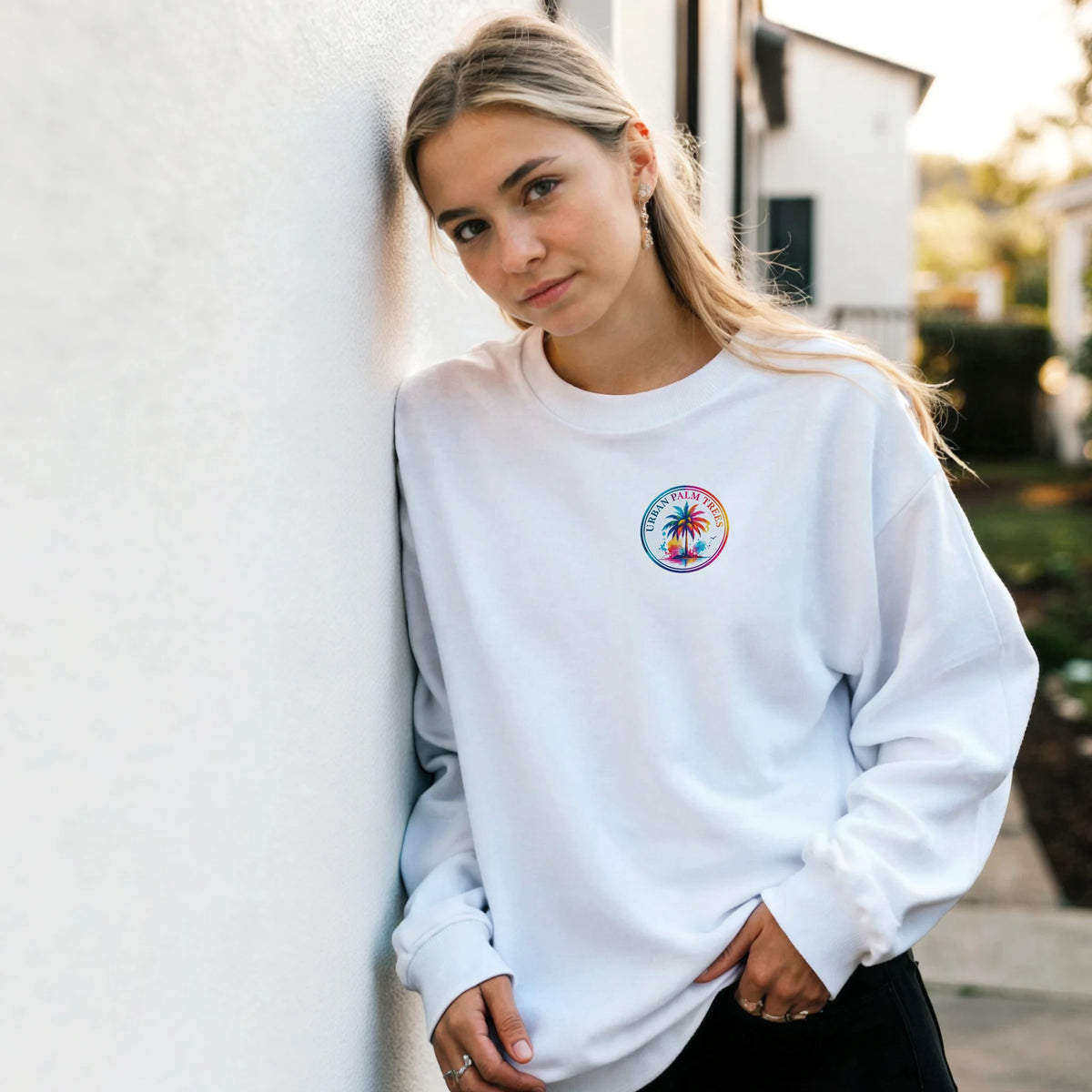 White sweatshirt featuring a colorful retro palm tree logo on the chest, styled as a casual tropical streetwear top.