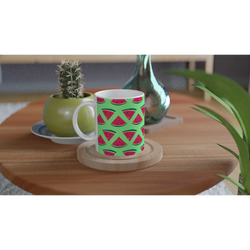 Cute ceramic coffee mug with green summer watermelon pattern on wooden coaster next to potted cactus.