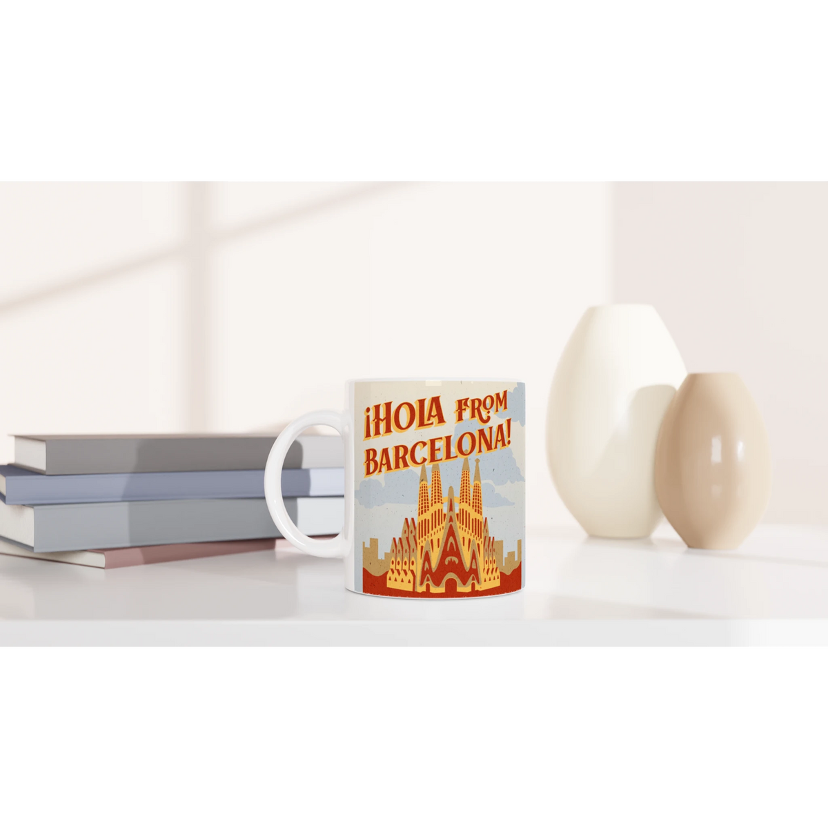Vintage Barcelona mug with retro postcard design Hola from Barcelona; coffee cup on a white desk.