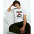 Male model wearing a white graphic T-shirt with a Japanese JDM car print, seated beside a white block.