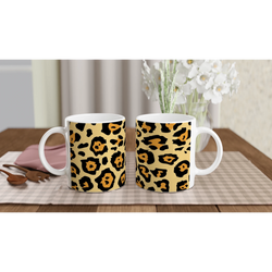 Classic leopard print mugs on a wooden table with a vase of white flowers in the background.