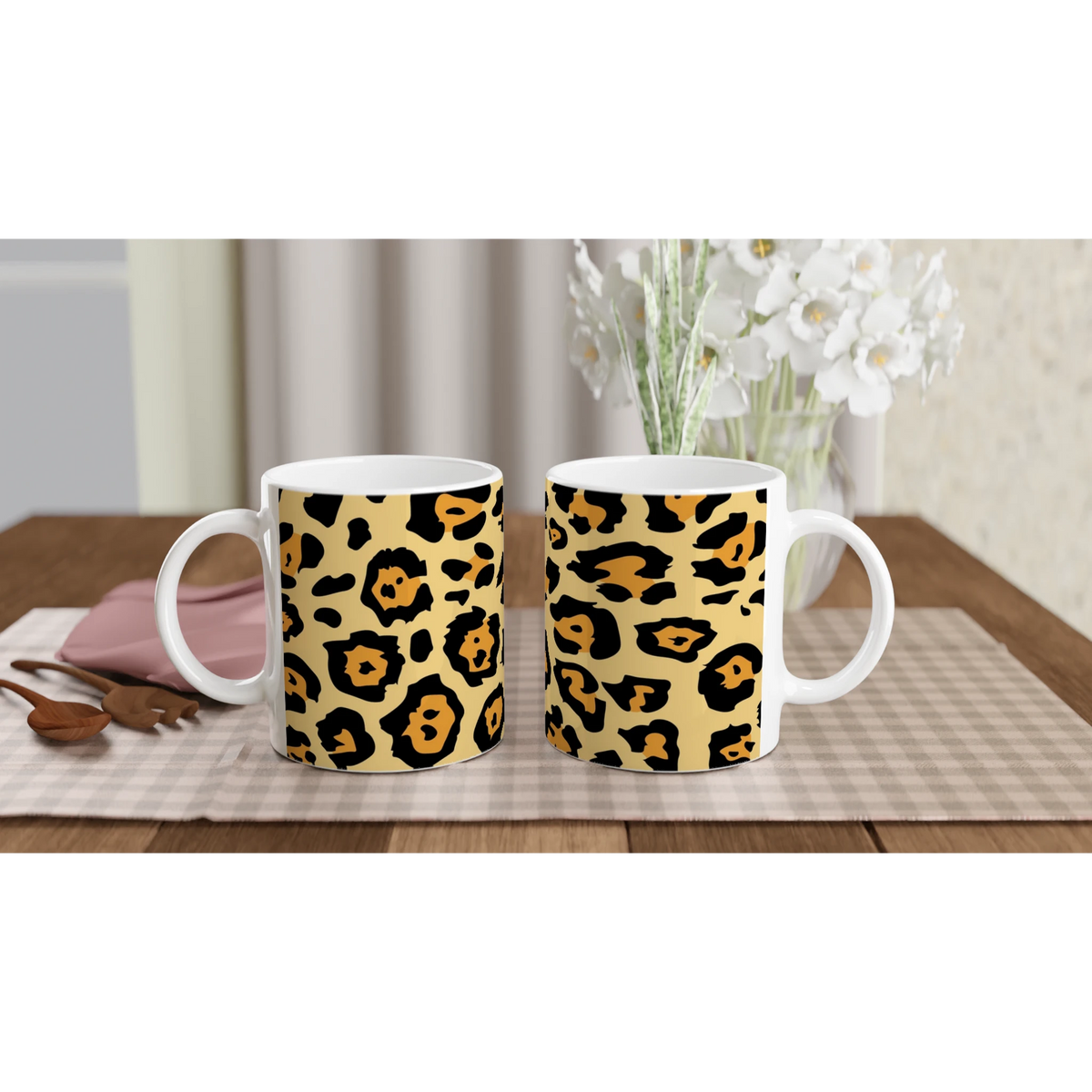 Classic leopard print mugs on a wooden table with a vase of white flowers in the background.