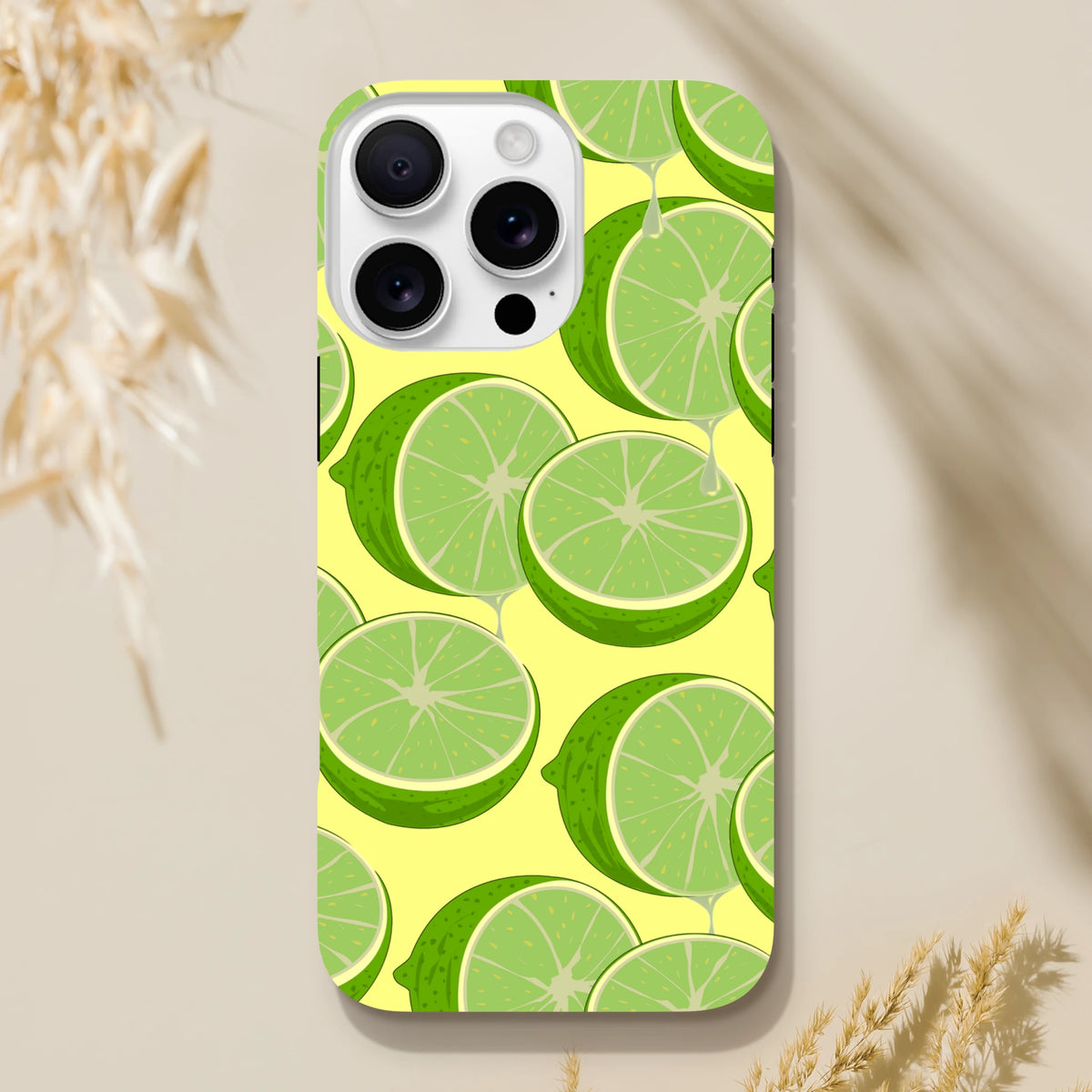 Fresh green lime slices with dripping juice on a yellow iPhone case, offering tough citrus style and impact protection.