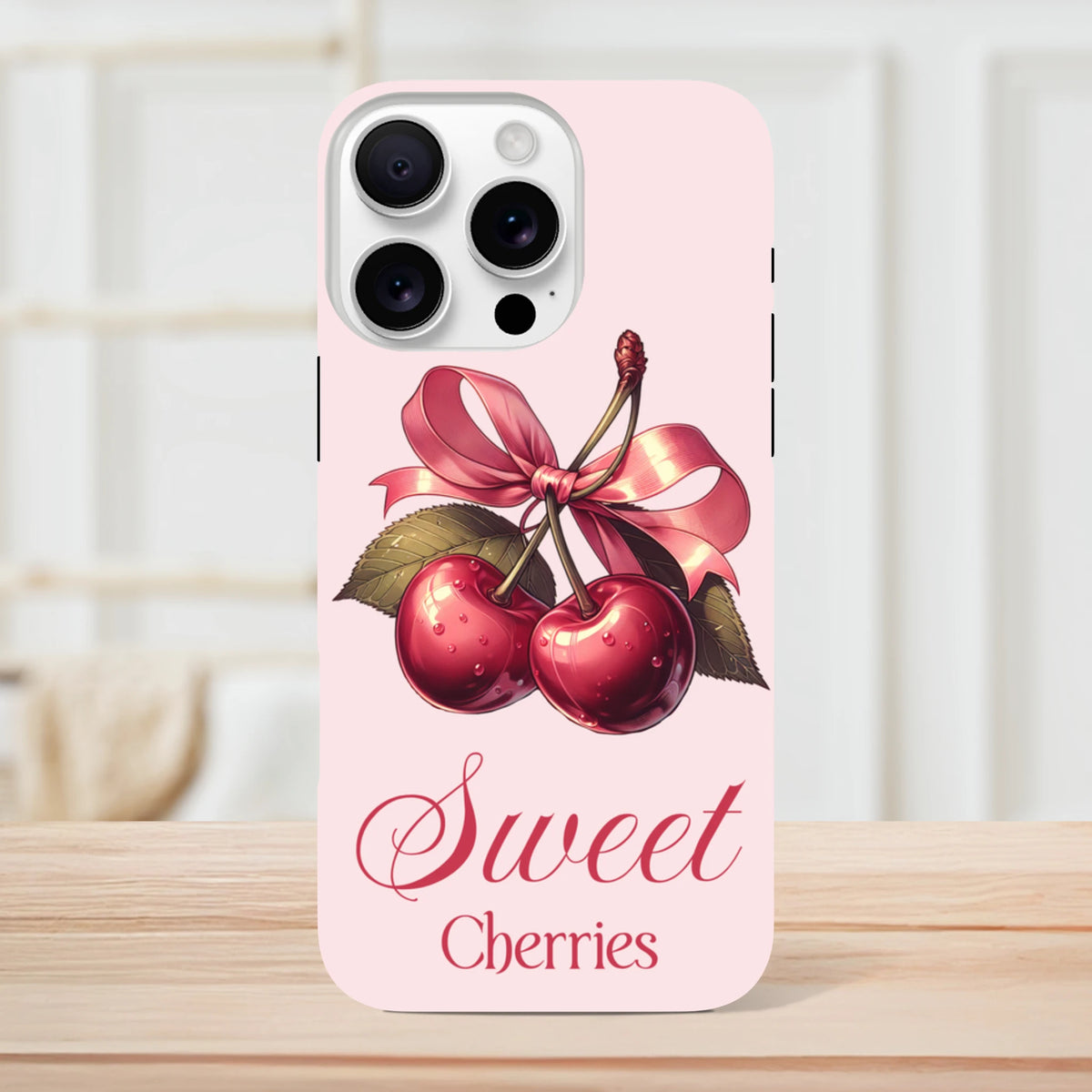 Vintage-style pink iPhone case featuring red cherries tied with a bow and Sweet Cherries script text.