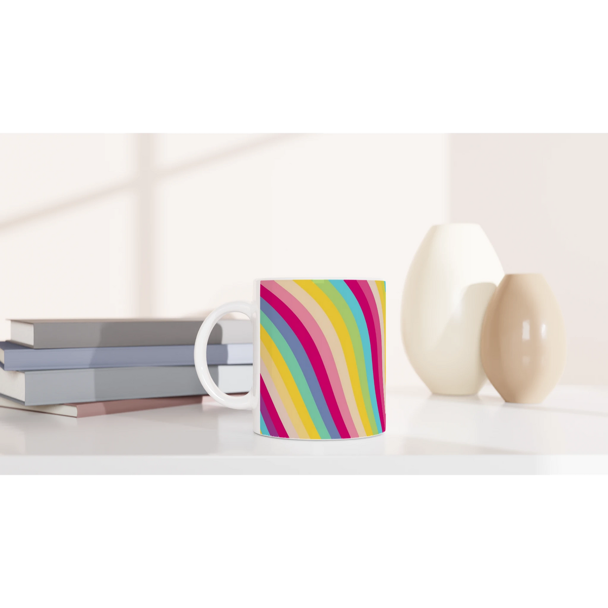 Retro rainbow-striped ceramic mug with bright diagonal stripes on white, sits on a desk with books.