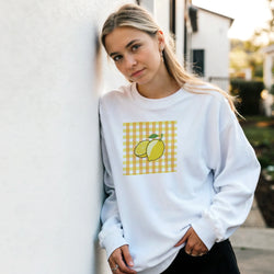 White sweatshirt featuring a retro yellow lemon graphic on a gingham background for a cute vintage fruit aesthetic.