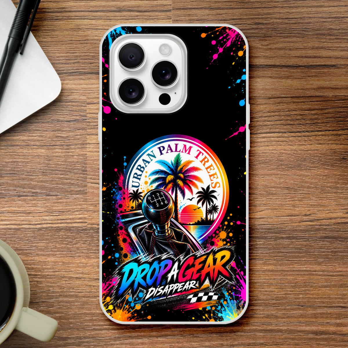 Vibrant iPhone case featuring a manual gear shifter, colorful palm tree sunset graphic, and "Drop A Gear" text with paint splatter effects.