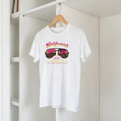 White women's T-shirt on a hanger with colorful retro California beach graphic.