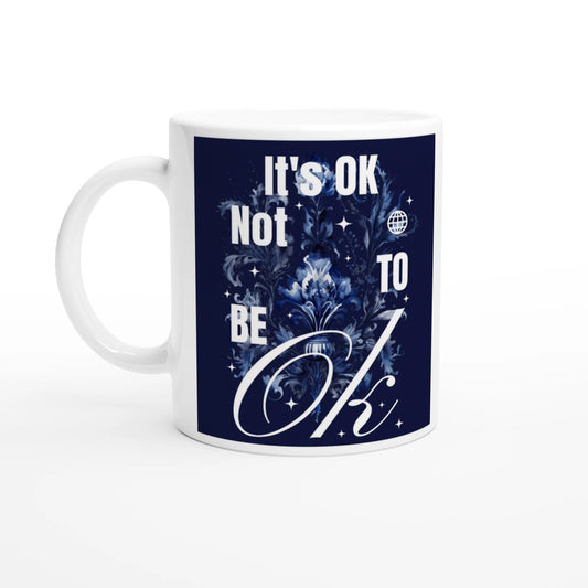 White ceramic mug with navy blue graphic reading It's OK Not To Be OK, surrounded by floral design.
