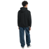 Back view of a man wearing a black DJ Bear hoodie with blue jeans and white sneakers.