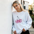 Pastel Y2K Cherries Sweatshirt with pink glitter cherry graphic worn by a woman outdoors.