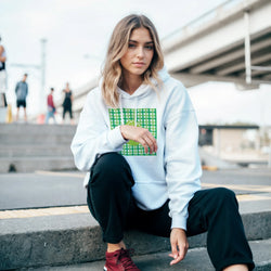 Woman wearing white hooded pullover with retro lime green gingham and fruit graphic, styled with black pants for urban streetwear.
