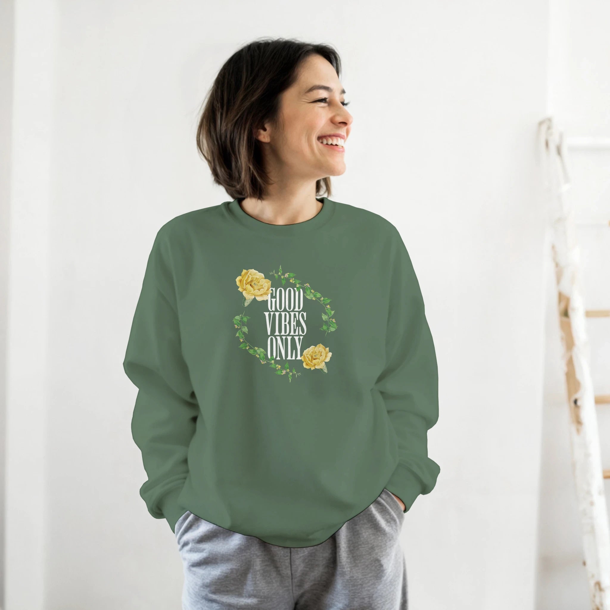Smiling woman wearing a green Mental Health jumper with a Good Vibes Only floral wreath graphic.