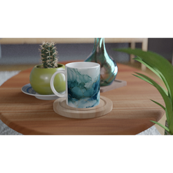 Blue Marble Mug with Ocean Abstract glaze, ceramic coffee cup on a wooden table beside a cactus and turquoise vase.