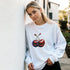 Woman wearing white cotton-blend Cherries Jumper graphic sweatshirt with red cherry print.
