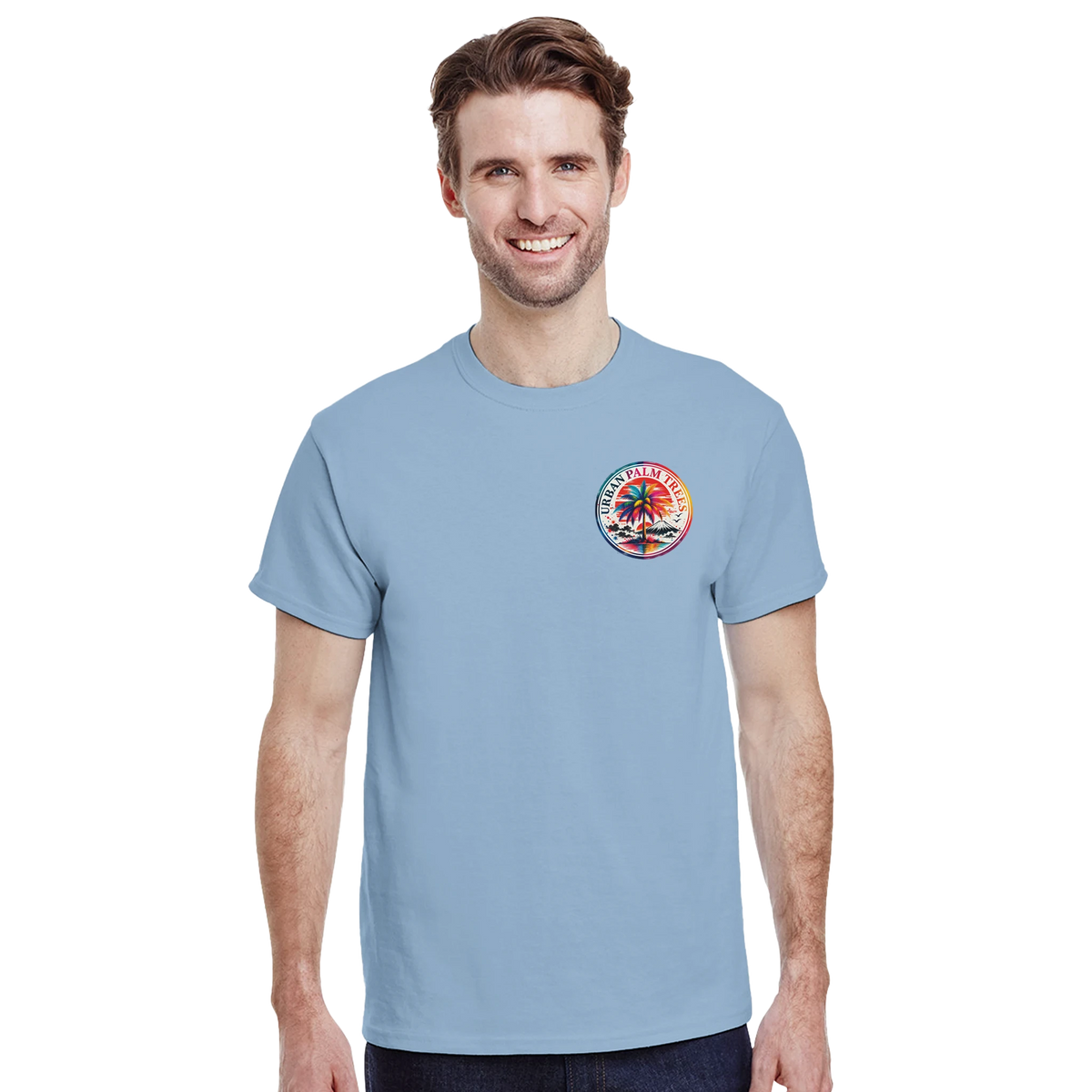 Man wearing light blue t-shirt with circular retro Urban Palm Trees graphic on chest. Casual streetwear top featuring colorful palm tree and mountain design.