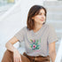 Paradise women's graphic T-shirt with tropical floral design on soft beige-gray fabric.