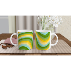 Two retro green-yellow wave mugs with rainbow swirl patterns on a wooden table, white flowers in background.