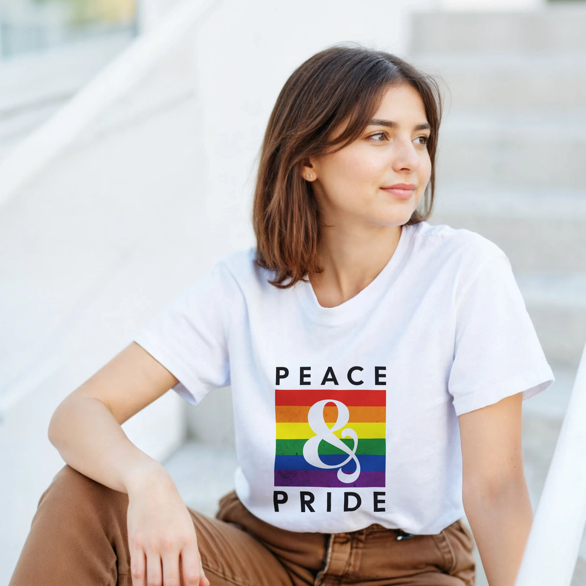 Woman wearing a white retro graphic tee with a vintage rainbow design and "Peace & Pride" text.